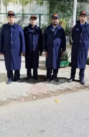 Four uniformed security guards standing together near an outdoor property gate