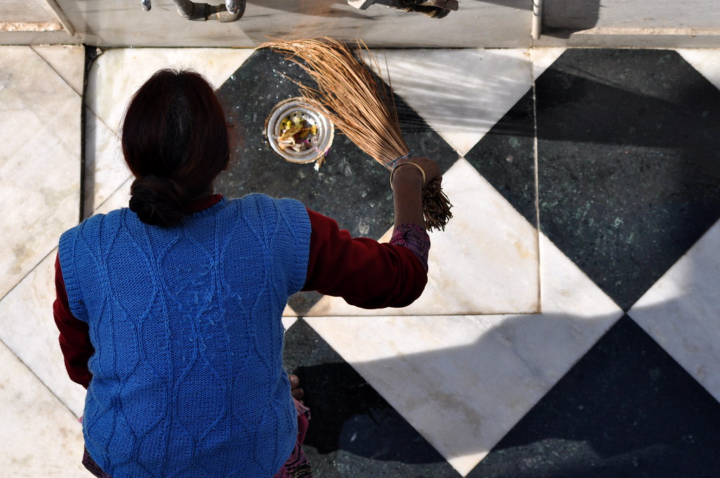 Woman sweeping a tiled floor inside a home